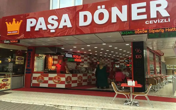 Kırmızı Paşa Döner tabelalı bir şubenin sipariş tezgahı ve oturma alanı