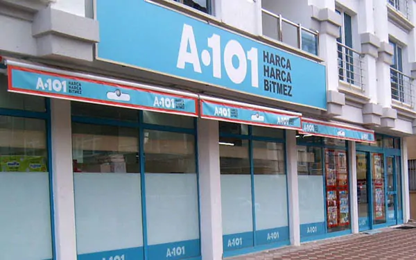 Cadde üzerindeki A101 mağazasının Harca Harca Bitmez yazılı mavi tabelası, A101 bayilik ücreti ne kadar? A101 bayilik veriyor mu, dükkan kiralama yolu Cadde üzerindeki A101 mağazasının Harca Harca Bitmez yazılı mavi tabelası