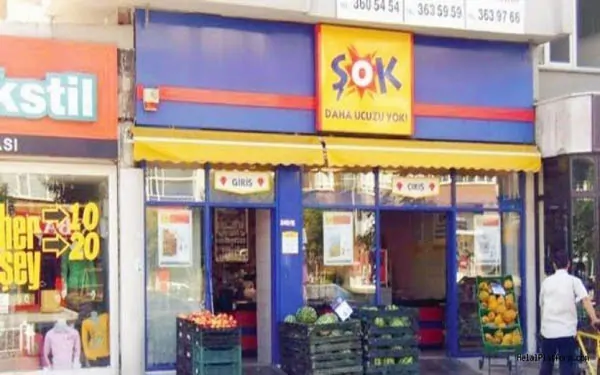 Mavi ve kırmızı cepheli eski konsept bir Şok mağazası ve önündeki manav kasaları