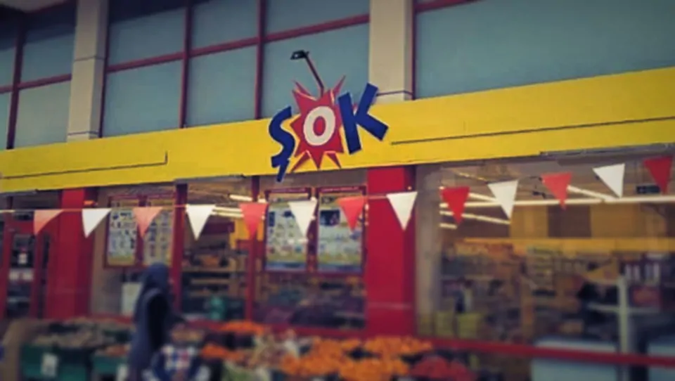 Şok logolu sarı tabela ve önünde süs bayrakları olan market cephesi